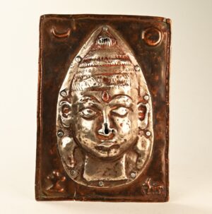 Antica placca devozionale indiana in rame con maschera d’argento di Virabhadra, manifestazione del dio Shiva, simbolo di forza spirituale e giustizia, oggetto rituale tradizionale dell’India.